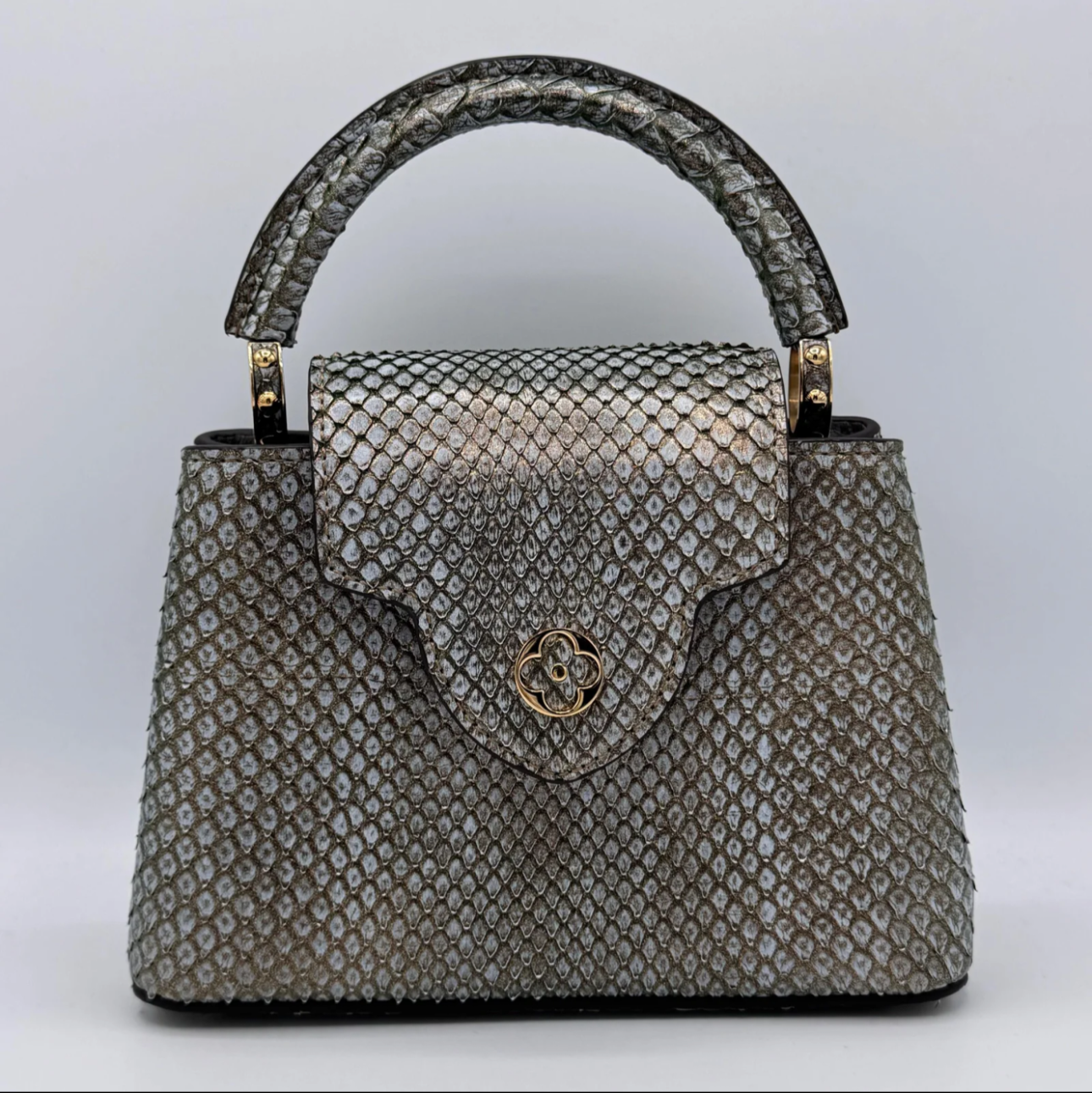 Silver textured handbag with a gold clasp on a light gray background